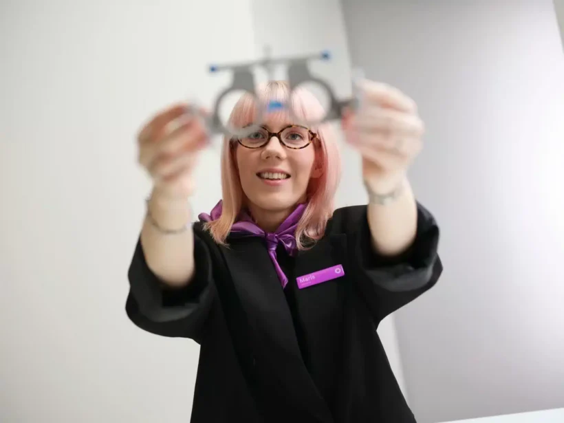 Naeratav optometrist ulatab prooviraame.